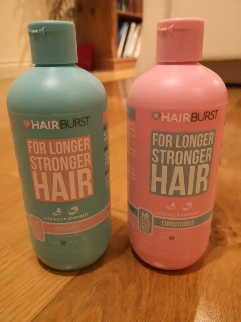 Hairburst shampoo and conditioner bottles, standing on a wooden floor.