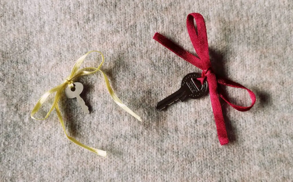 Two small keys, with a red and yellow ribbon tied to them in a bow