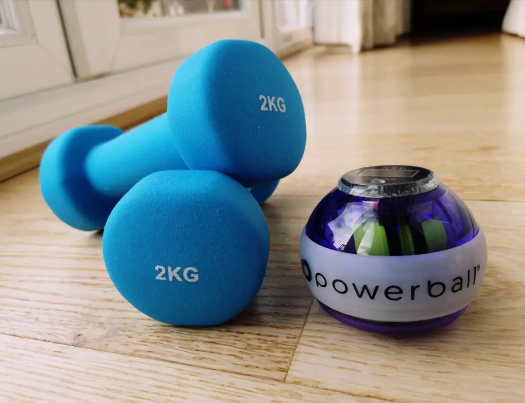 a pair of blue 2kg weights and a purple and white powerball on a wooden floor