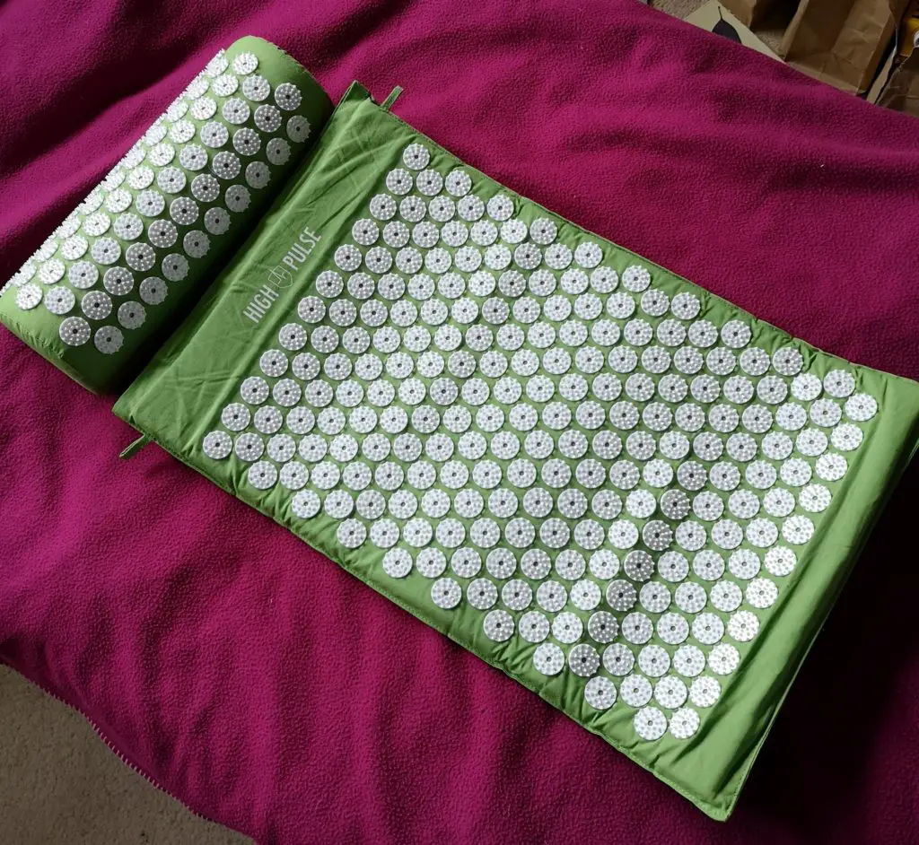 My green High Pulse acupressure mat, laid out on my bed