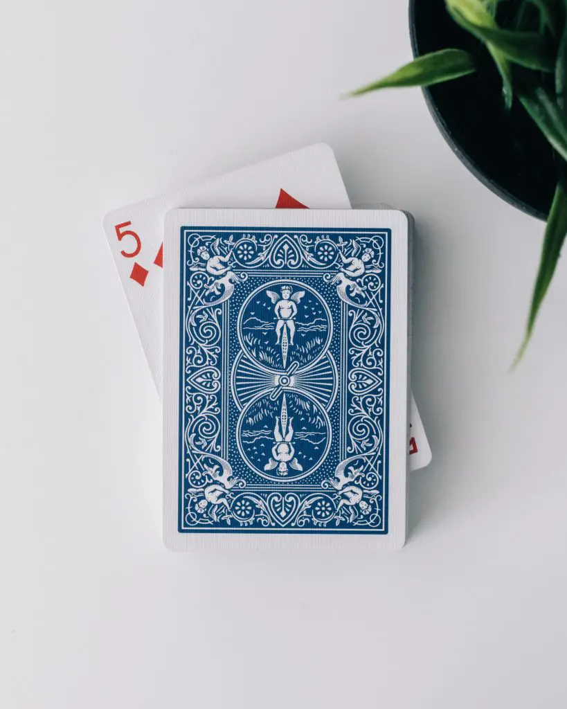 A pack of cards, blue backed, with the 5 of diamonds poking out.