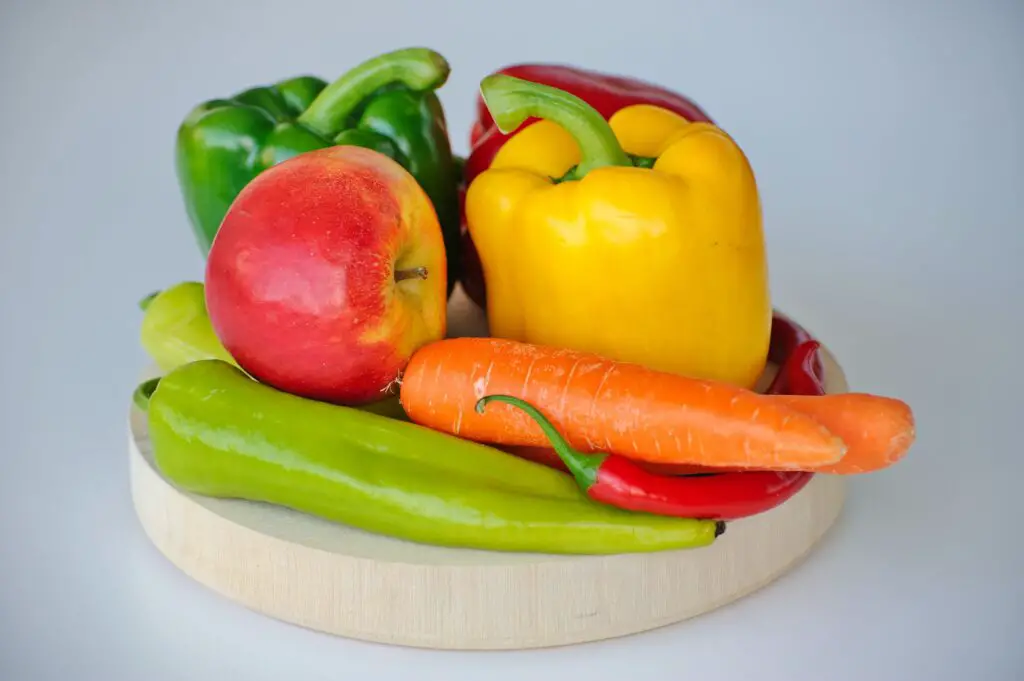 A platter of colourful bell peppers, chillis, apples and carrots