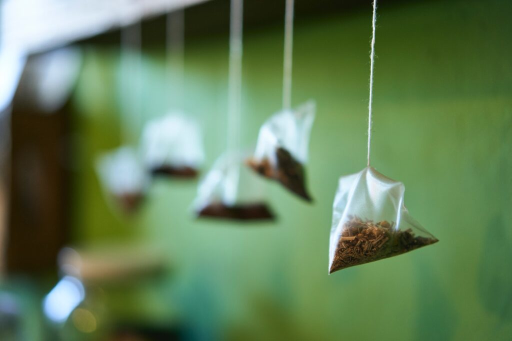 Herbal teabags hanging from their strings in front of a green background