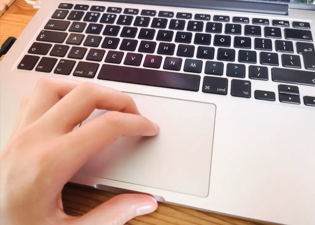 The keyboard of a silver Macbook Pro. My hand is on the trackpad.