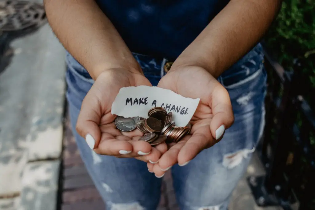 A pair of cupped hands holding coins and a piece of paper saying 'make a change'.