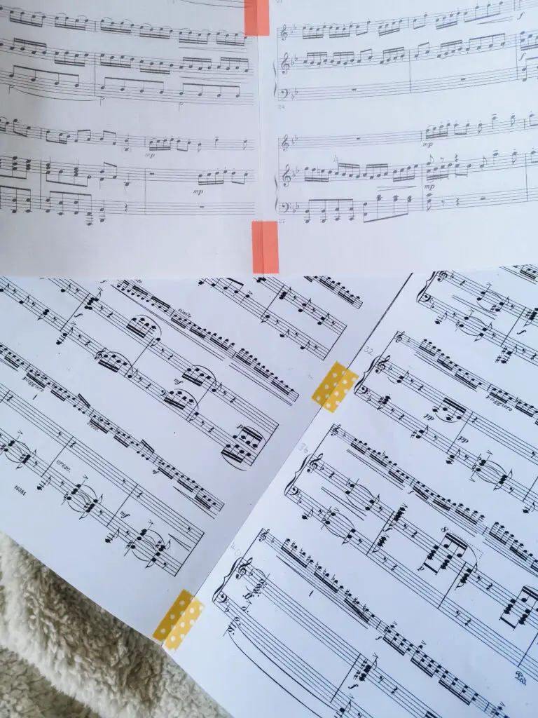 Several pages of sheet music that have been stuck together with pink and yellow washi tape.