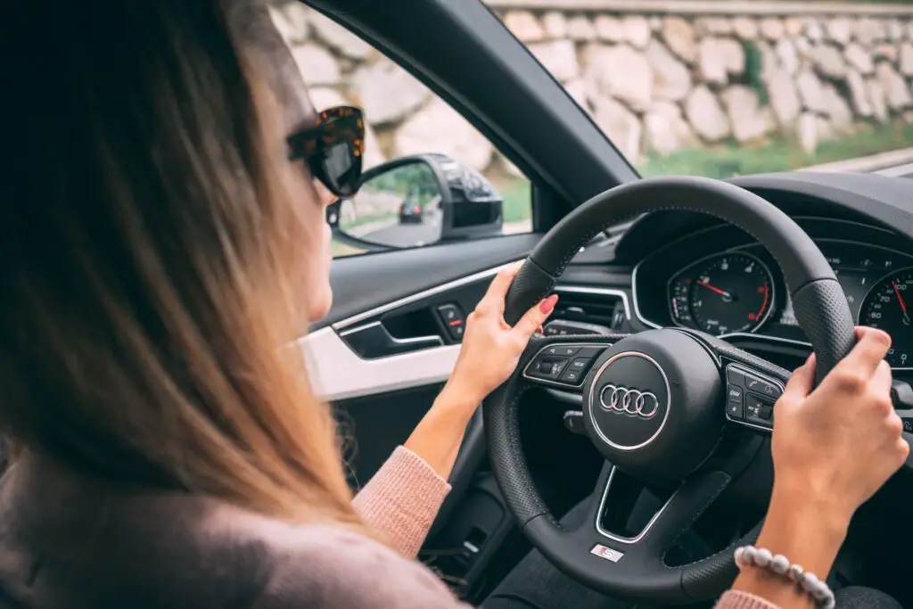 A woman wearing sunglasses driving a car.