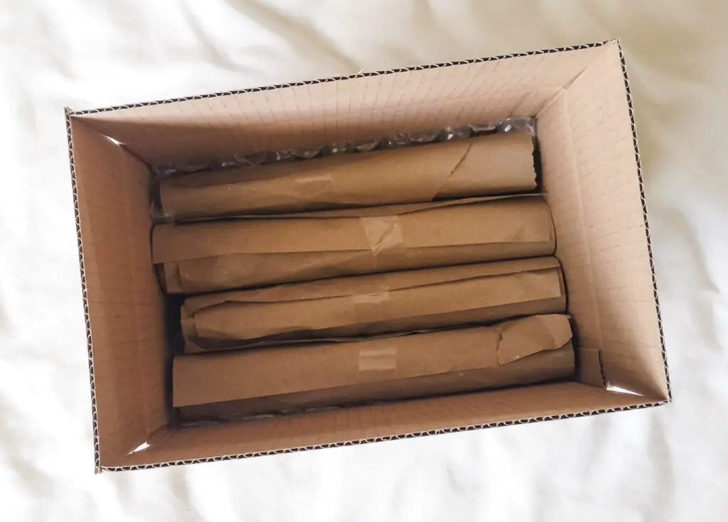 4 rolls of brown paper inside a cardboard box.