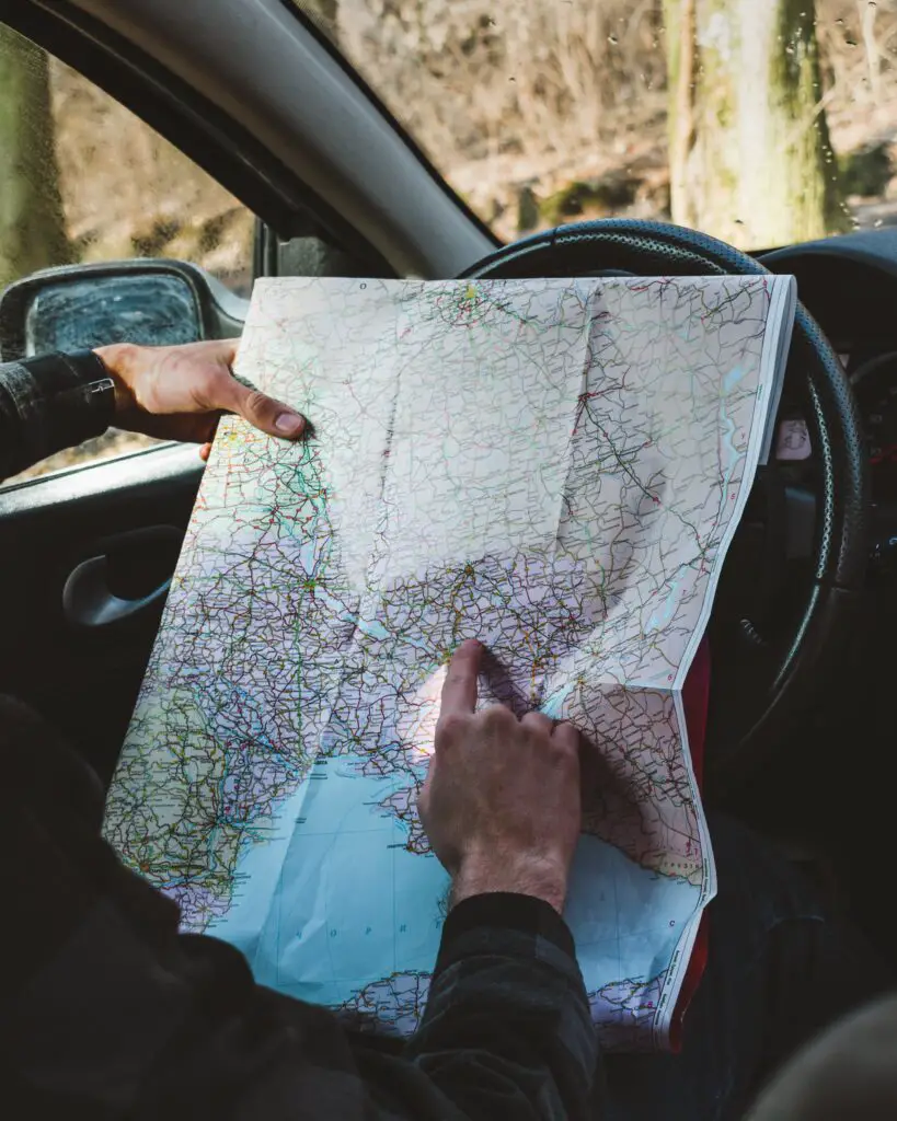 Someone looking at a road map at the wheel of a car.