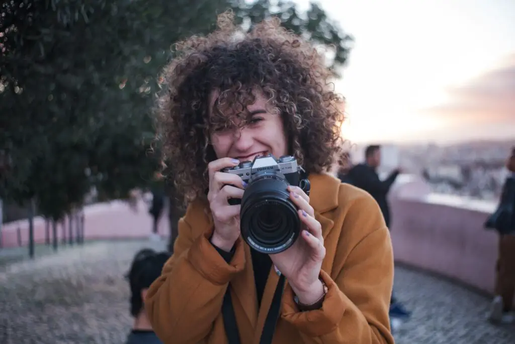 A woman holding a camera and smiling.