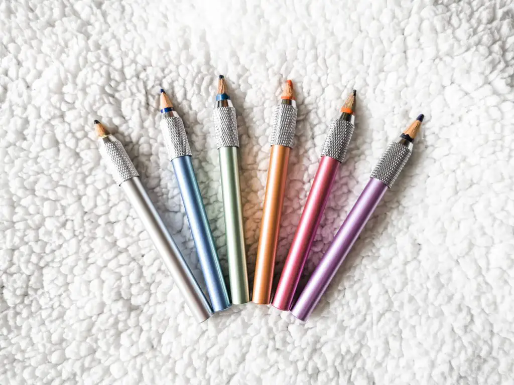 Six colourful pencil extenders with short pencils in them.