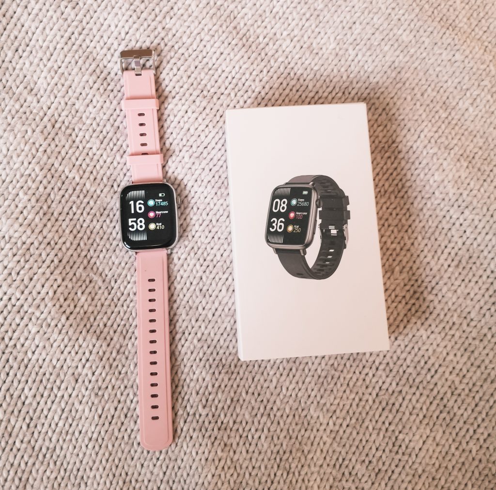 A pink Misirun Smart Watch next to its packaging box