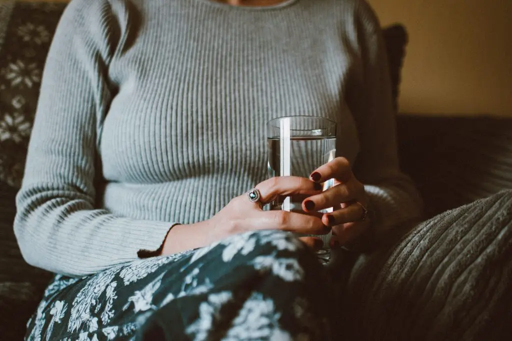 A seated woman holding a glass of water.