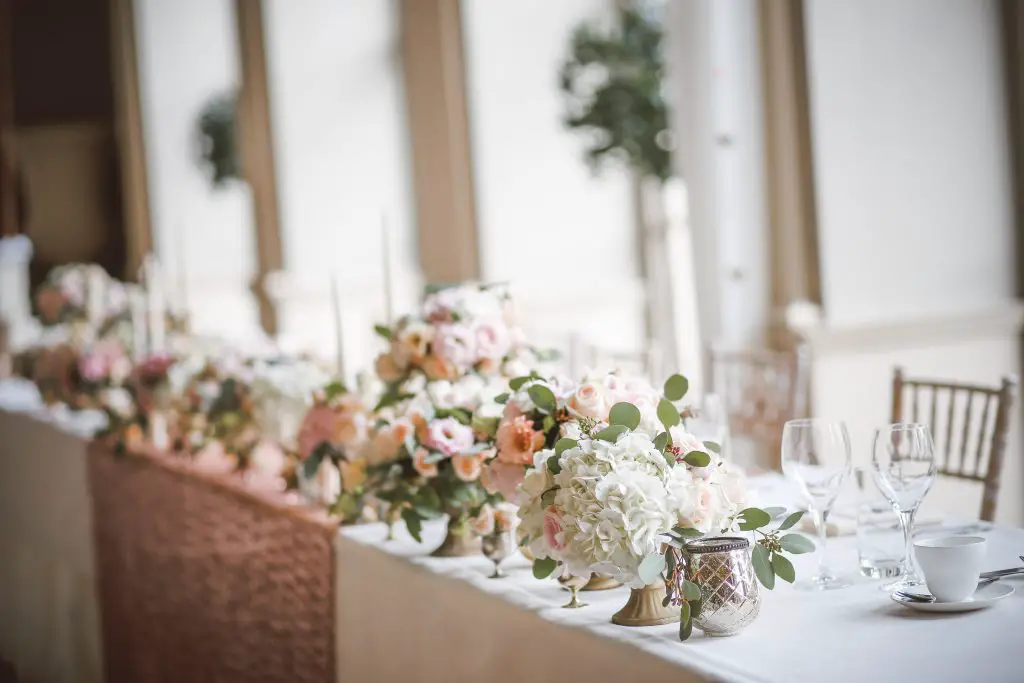 A wedding table with several vases of flowers on it.