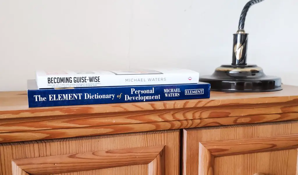 Stacked paperback copies of Becoming Guise-Wise and The Element Dictionary of Personal Development by Michael Waters.