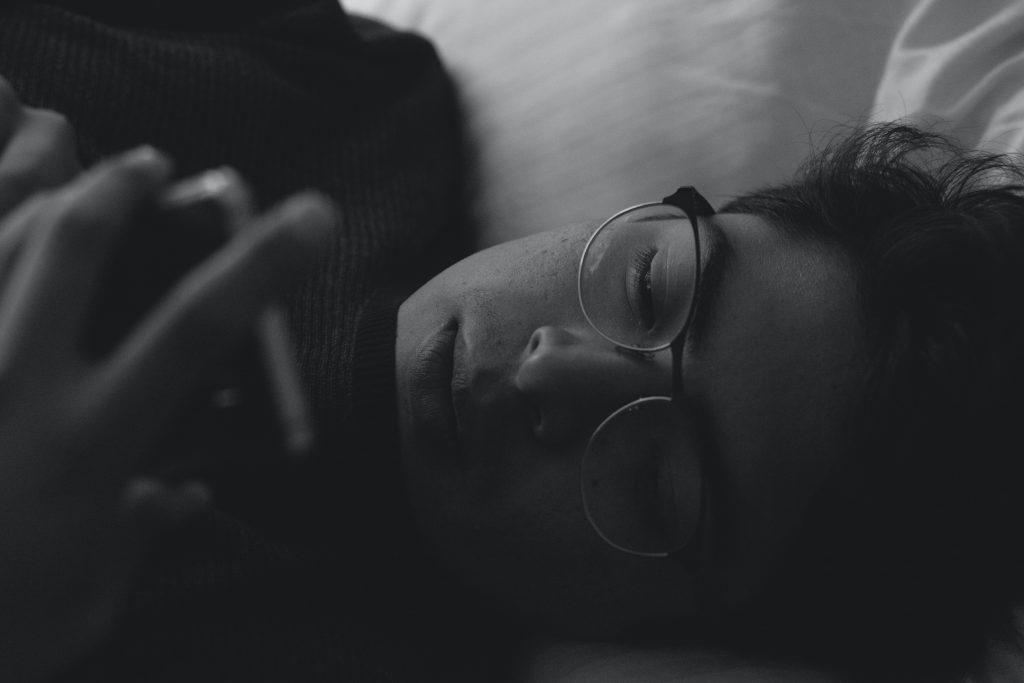 A man looking at his phone while lying down.