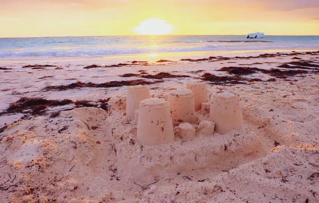 A sandcastle on a beach at sunset.