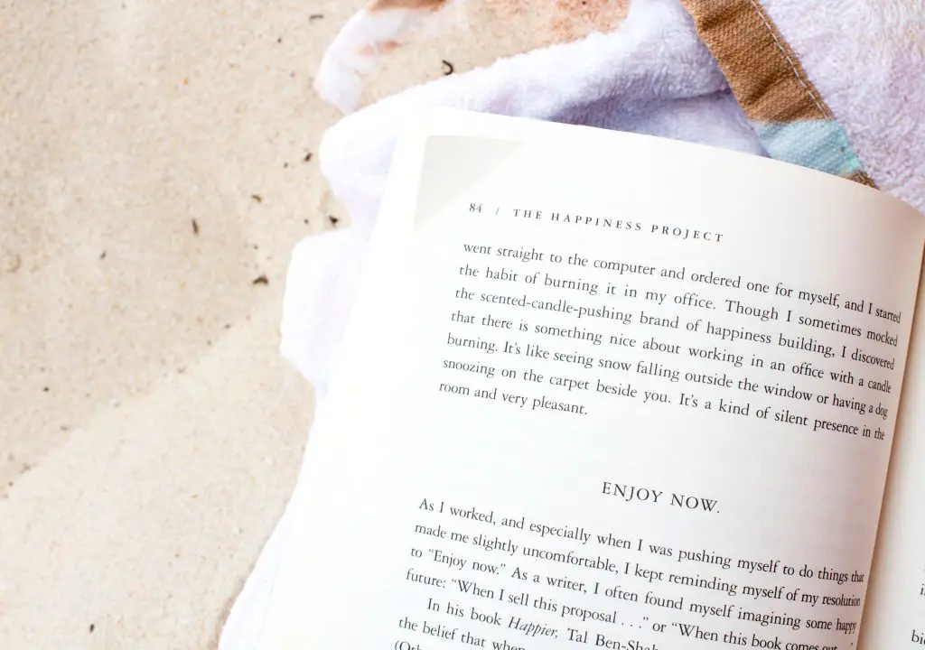 An open book with a towel and sand in the background.