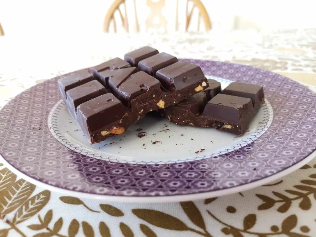 A bar of FATSO chocolate, broken in half, on a purple and white plate on a table.