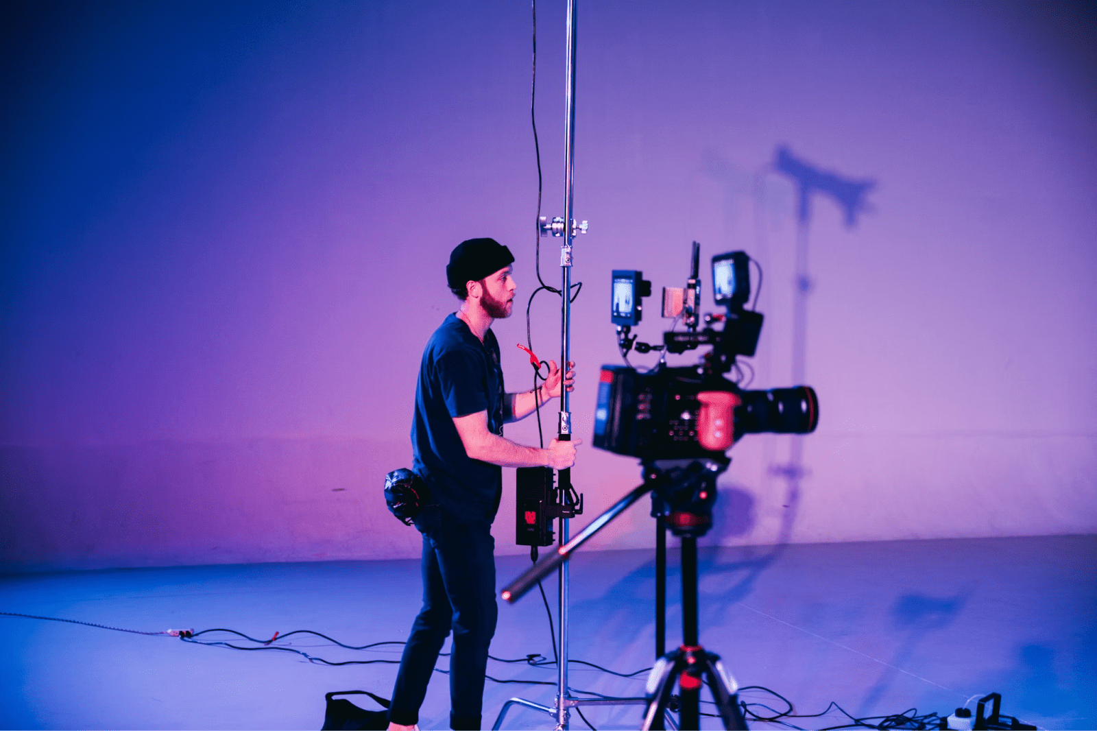 A man using recording equipment in a studio, basked in purple light.