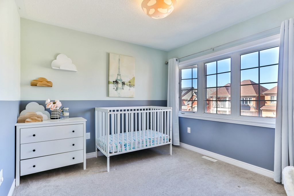 A nursery in blue and green colours with a view out the window.