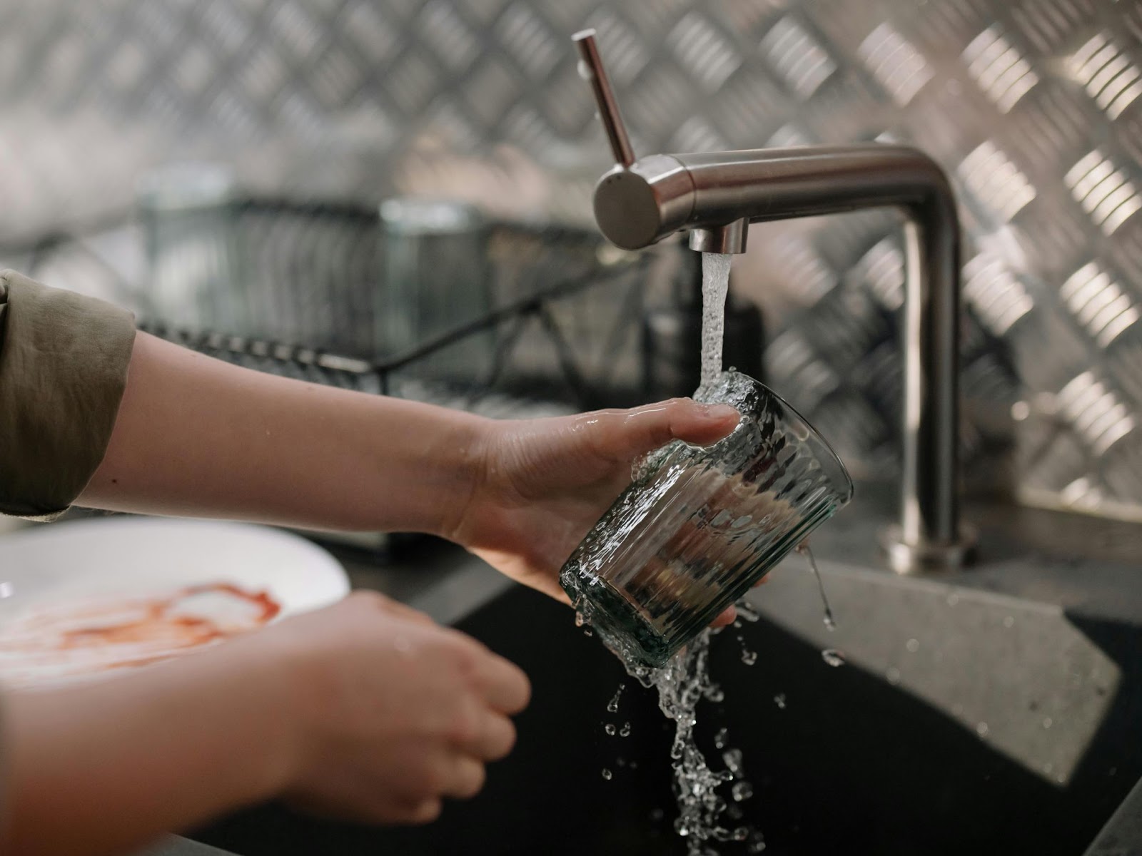 A person running a glass under a tap.