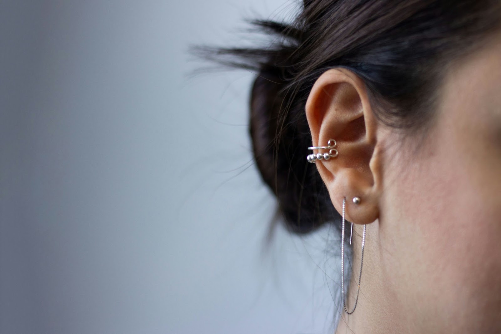 An ear with several piercings with jewellery in them.