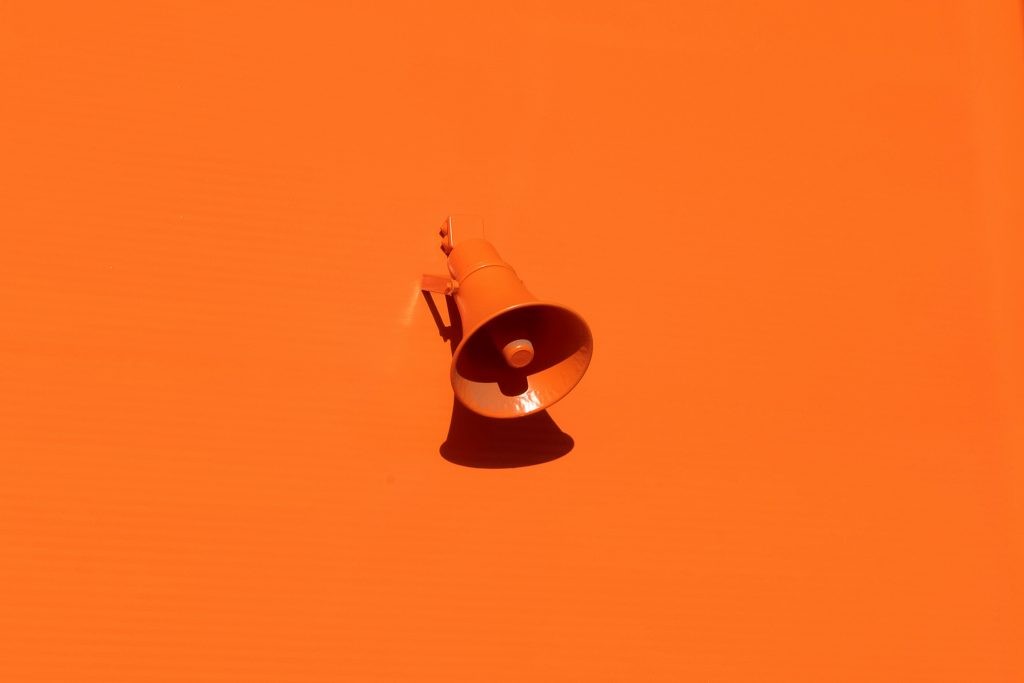 An orange megaphone on a plain orange background.