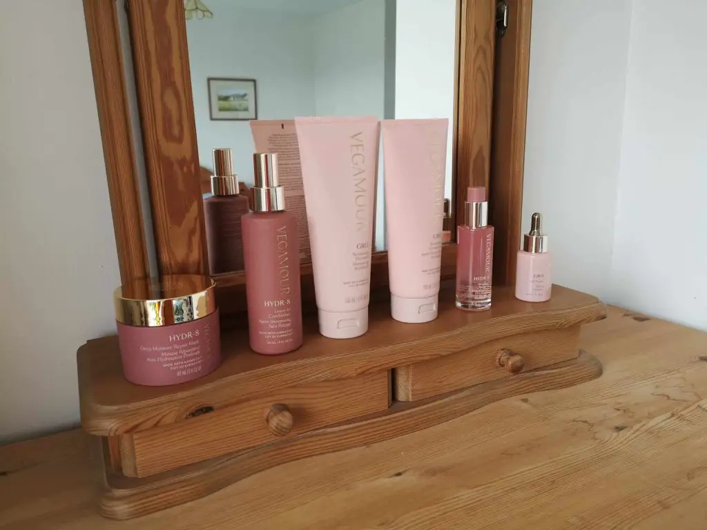 Six Vegamour hair products displayed on a dressing table.