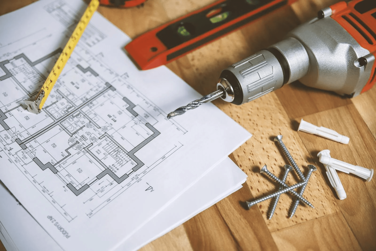 A floor plan of a house, surrounded by tools including a drill, tape measure and screws.