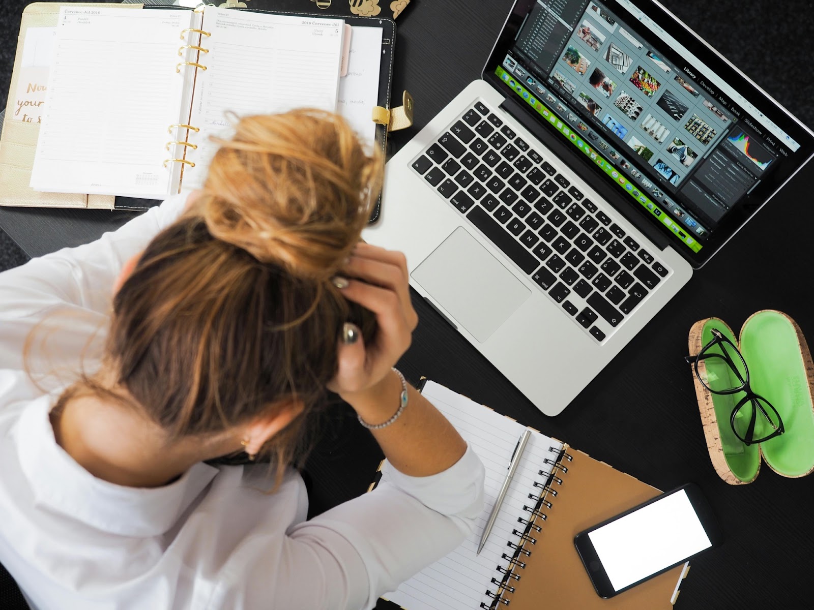 A woman sitting at a desk with her head in her hands.
