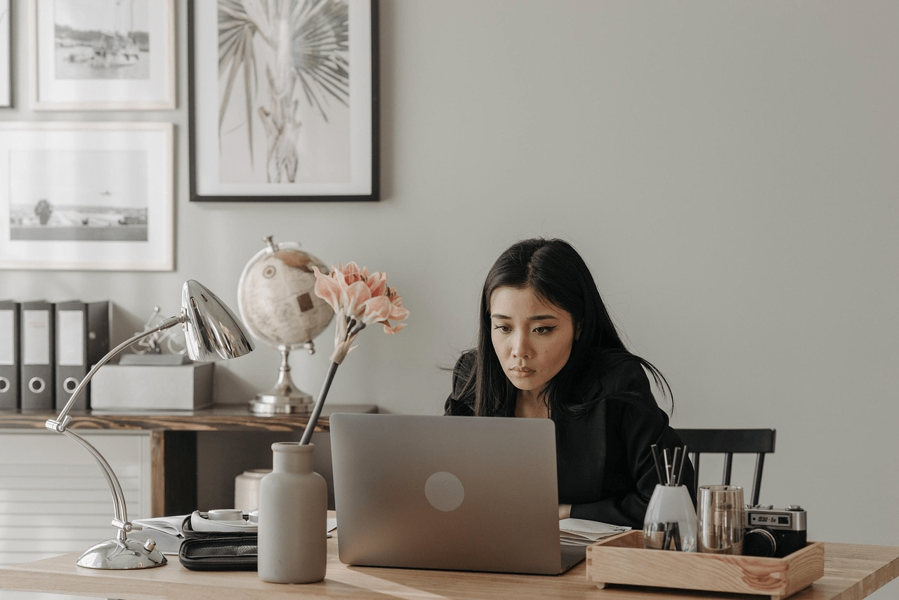 A woman sitting at a desk and staring at a laptop screen.