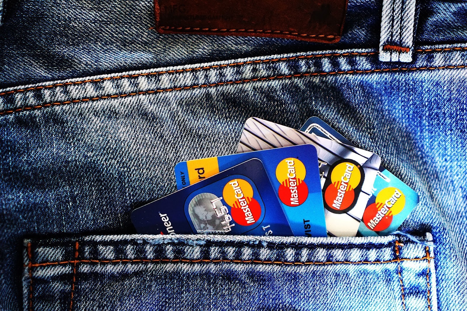 A jeans pocket with several credit cards poking out of it.