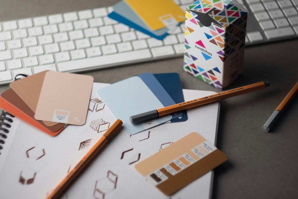A desk covered in branding materials including colour swatches, pencils and a notepad.