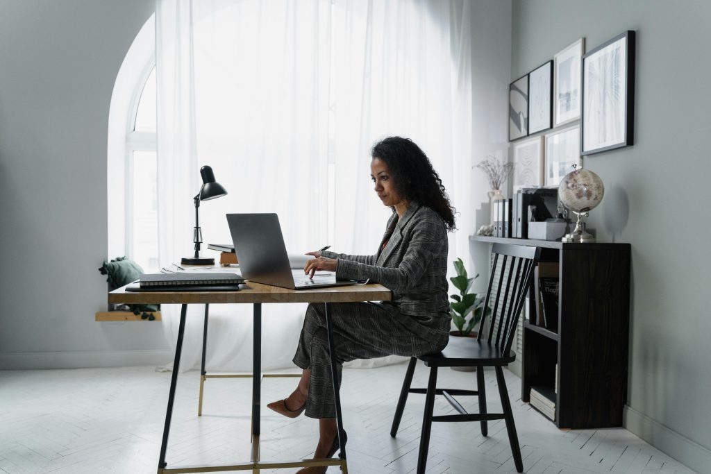 A woman sitting at a desk, working on a laptop.