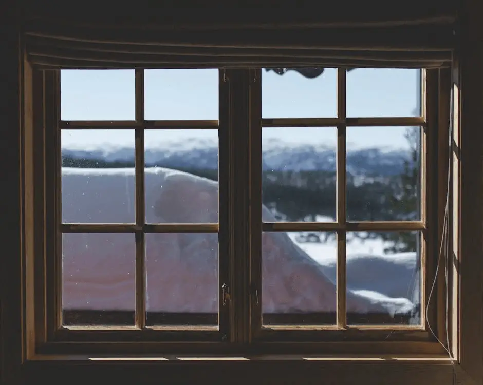 A wooden window looking out over a snowy scene.