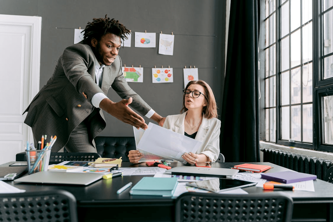 A man and a woman arguing in frustration over some work.