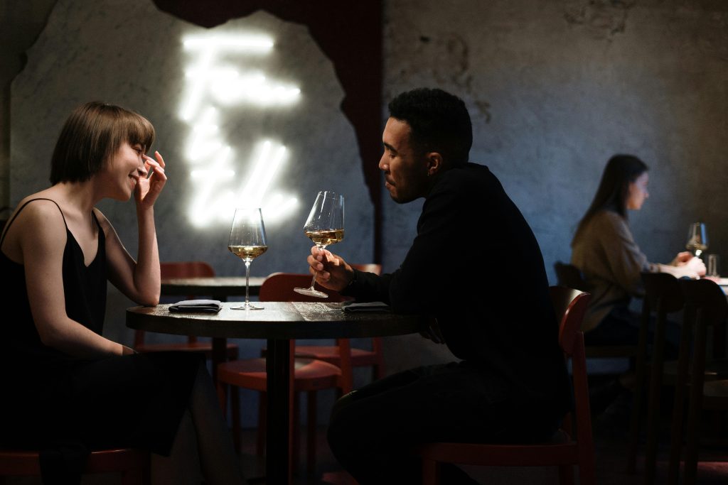 A man and a woman seated at a table, drinking wine together.