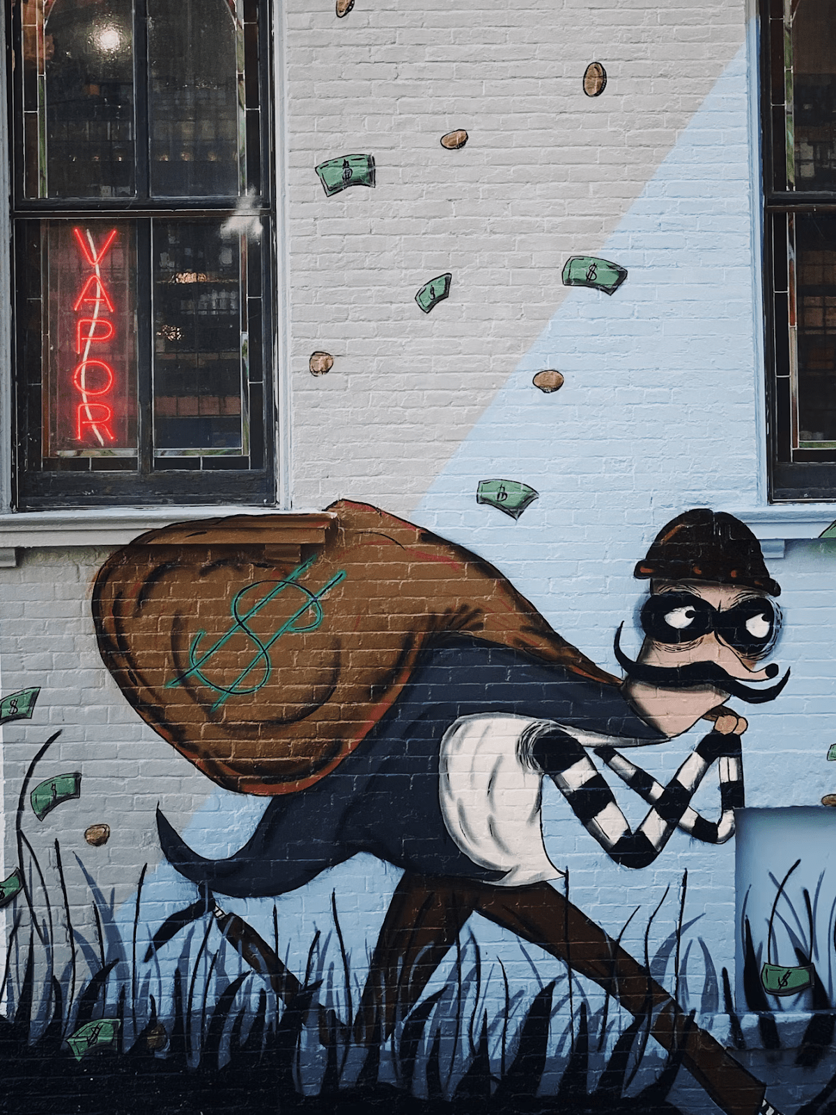 Graffiti of a burglar painted onto a white brick wall.